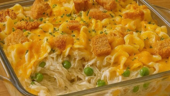 A golden, bubbly chicken noodle casserole in a glass dish with melted cheese on top.