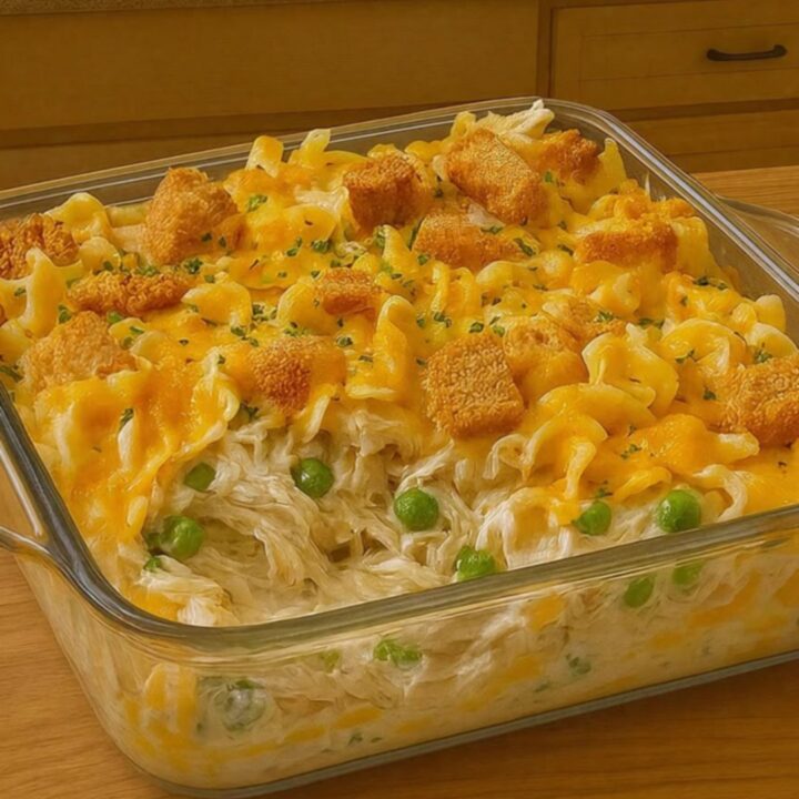 A golden, bubbly chicken noodle casserole in a glass dish with melted cheese on top.