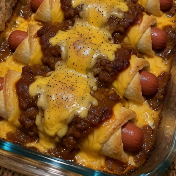 A close-up of golden brown chili cheese dog crescent rolls in a glass baking dish with steam rising.