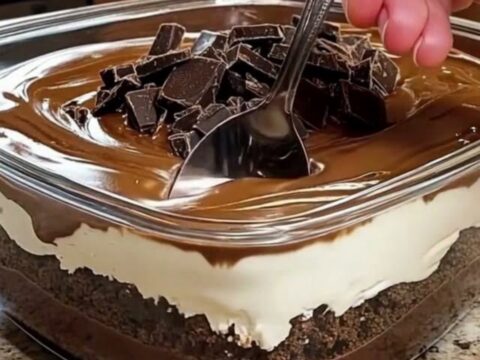 A decadent multi-layered chocolate dessert in a glass dish with visible layers of pudding, cream, and ganache.