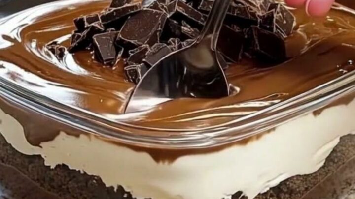 A decadent multi-layered chocolate dessert in a glass dish with visible layers of pudding, cream, and ganache.