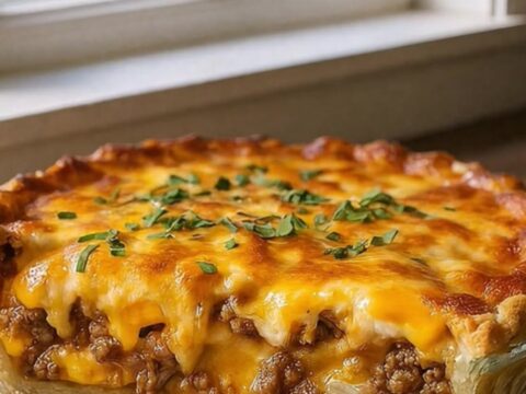 A golden, freshly baked cheeseburger pie in a glass dish, viewed from above in a bright kitchen.