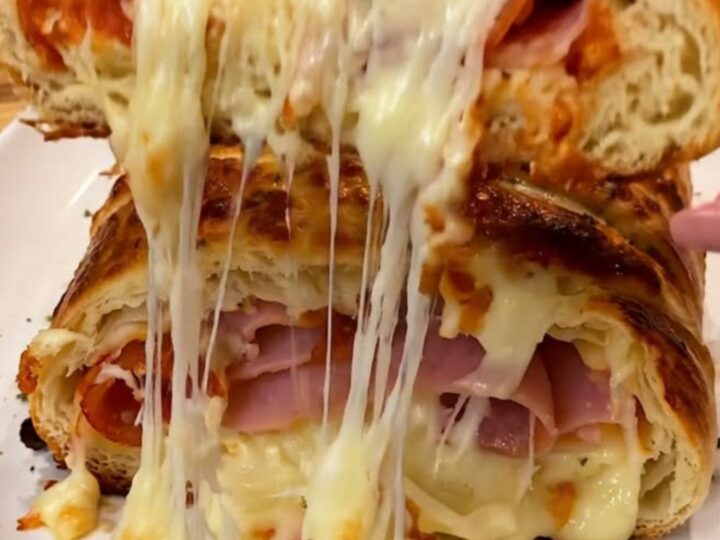 A golden-brown pizza stromboli sliced open to reveal melted mozzarella, ham, and pepperoni.