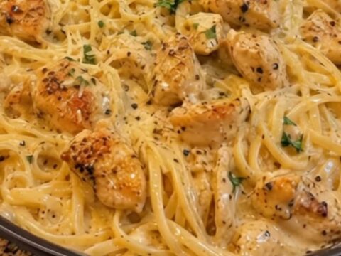 A close-up view of creamy garlic butter chicken linguine served in a white bowl with a fork twirling the pasta.