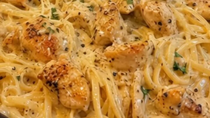 A close-up view of creamy garlic butter chicken linguine served in a white bowl with a fork twirling the pasta.