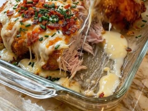 Golden baked chicken breasts topped with melted cheddar cheese and crispy bacon strips in a glass dish.