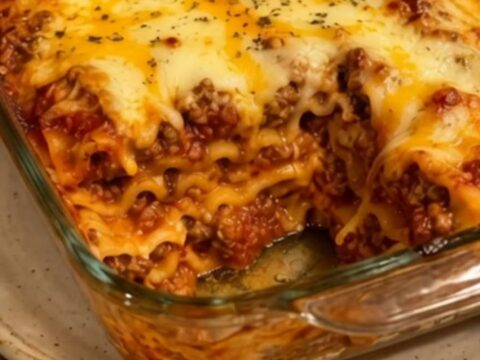 A close-up shot of a steaming slice of beef lasagna with a dramatic cheese pull on a white plate.