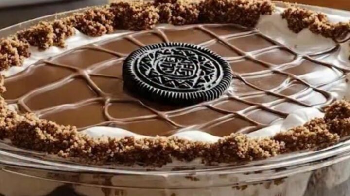 A close-up of a chilled Oreo chocolate cake in a glass dish with distinct layers of cake, cream, and ganache.