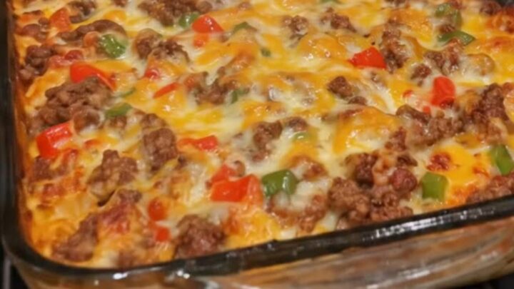 A cheesy ground beef casserole in a rectangular glass dish with visible steam and melted cheese pulls.