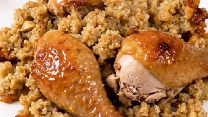 A top-down view of a black slow cooker filled with chicken, creamy soup, stuffing, and broth before cooking.