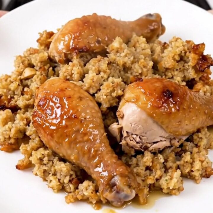 A top-down view of a black slow cooker filled with chicken, creamy soup, stuffing, and broth before cooking.