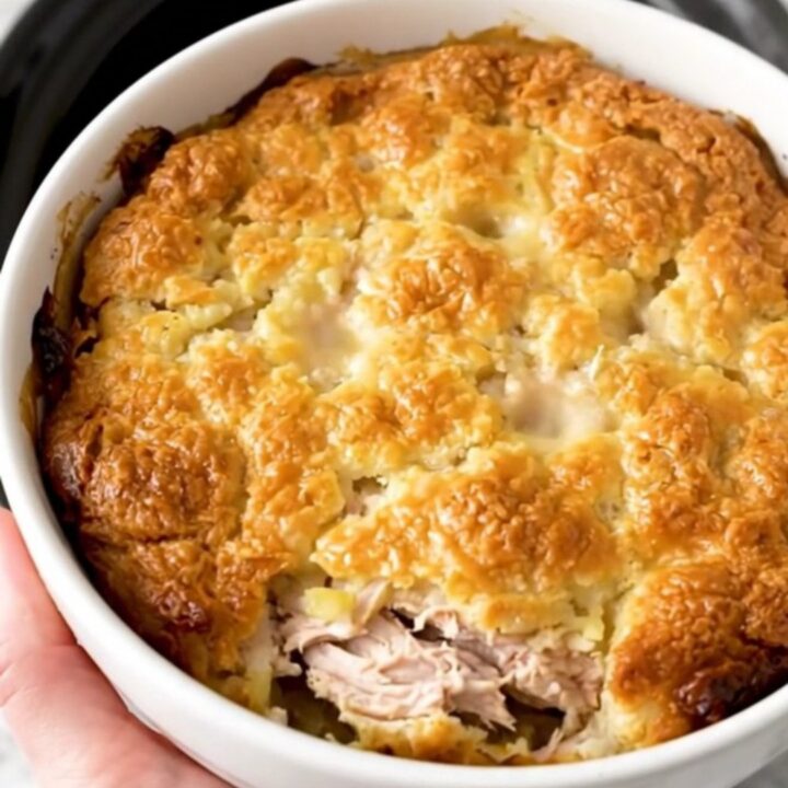 A top-down view of a slow cooker filled with chicken, vegetables, and a creamy herb sauce.