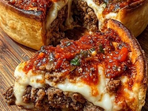 A golden, deep-dish meat pie on a wooden board, showcasing a crispy crust and a rich, cheesy filling.