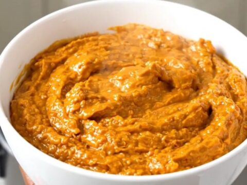 A white bowl filled with creamy, shredded buffalo chicken dip, steaming and glossy.