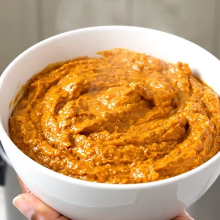 A white bowl filled with creamy, shredded buffalo chicken dip, steaming and glossy.