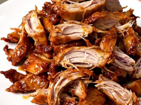 A slow cooker filled with shredded Mississippi chicken featuring pepperoncini peppers and a savory sauce.