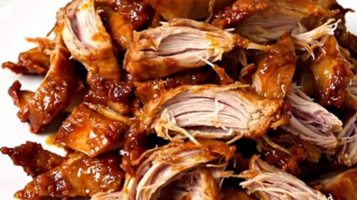 A slow cooker filled with shredded Mississippi chicken featuring pepperoncini peppers and a savory sauce.