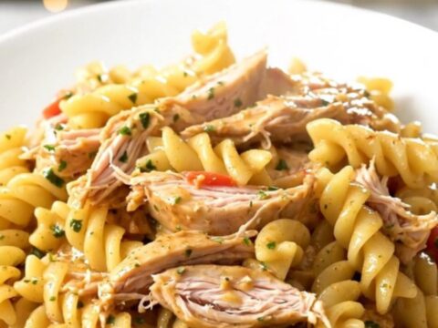 A top-down view of a slow cooker filled with chicken, cherry tomatoes, and a wheel of garlic herb cheese.