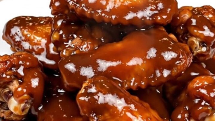A plate of glossy, dark-glazed chicken wings freshly removed from the slow cooker.
