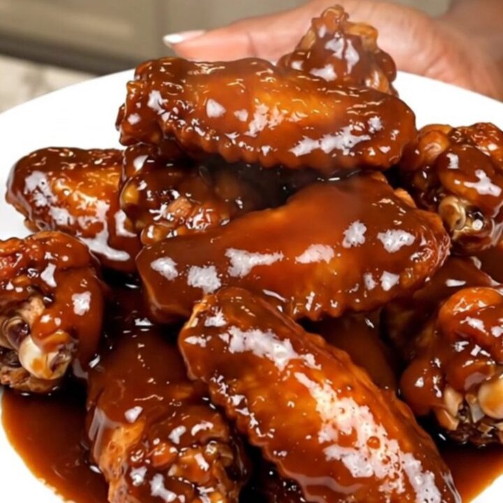 A plate of glossy, dark-glazed chicken wings freshly removed from the slow cooker.