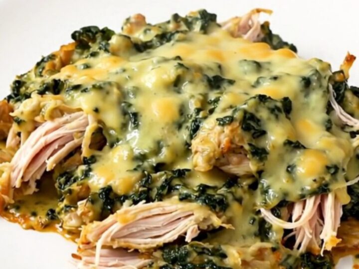 A close-up of creamy spinach artichoke chicken in a slow cooker.