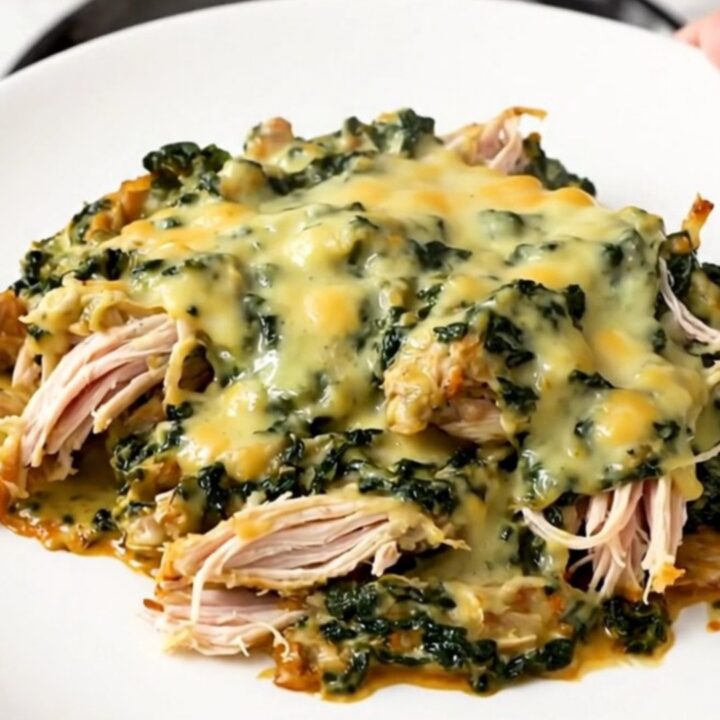 A close-up of creamy spinach artichoke chicken in a slow cooker.