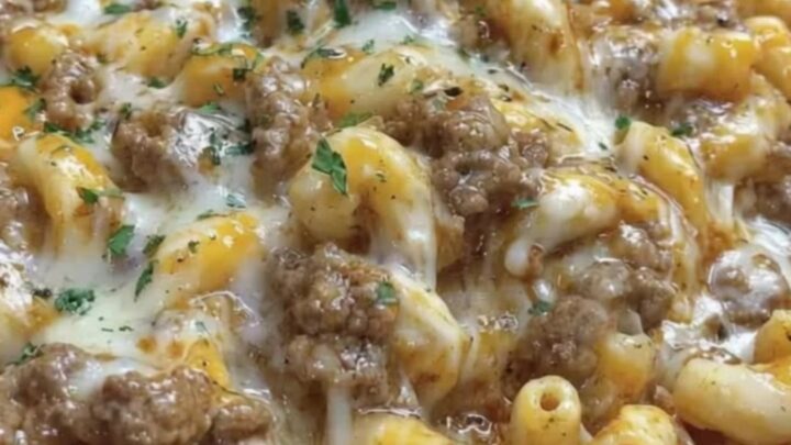 A close-up of a skillet filled with bubbling cheesesteak hamburger helper topped with melted cheese and parsley