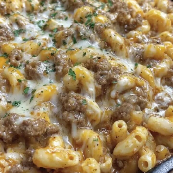 A close-up of a skillet filled with bubbling cheesesteak hamburger helper topped with melted cheese and parsley