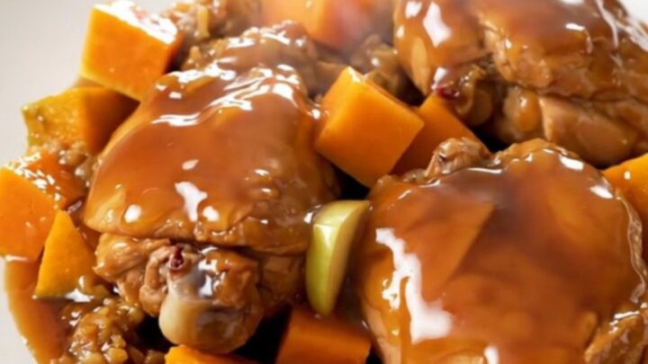 A close-up of tender chicken thighs with roasted butternut squash and apple wedges on a white plate.