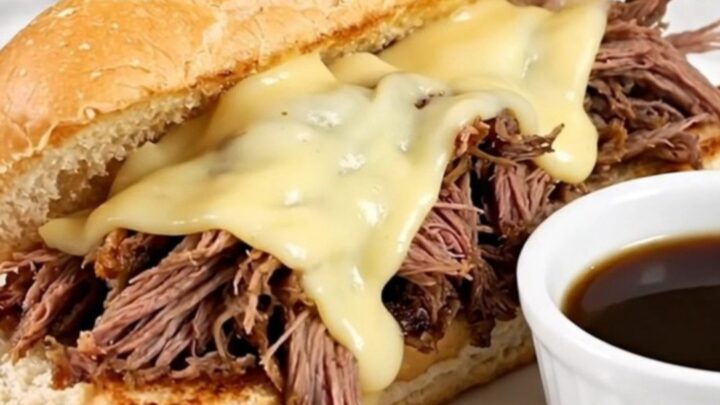A warm, toasted hoagie roll filled with shredded beef and melted provolone cheese on a white plate.