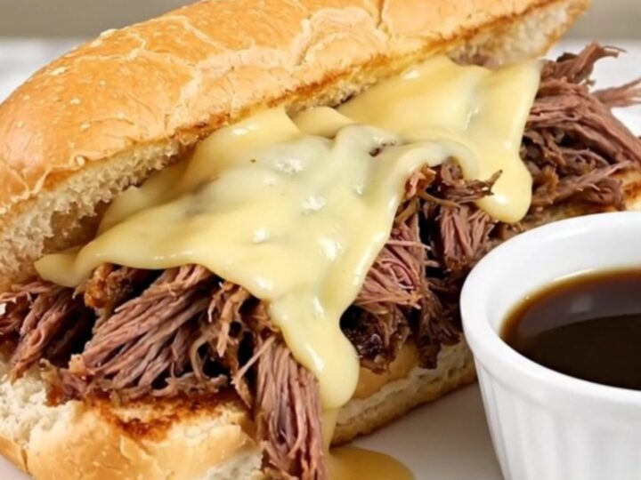 A warm, toasted hoagie roll filled with shredded beef and melted provolone cheese on a white plate.