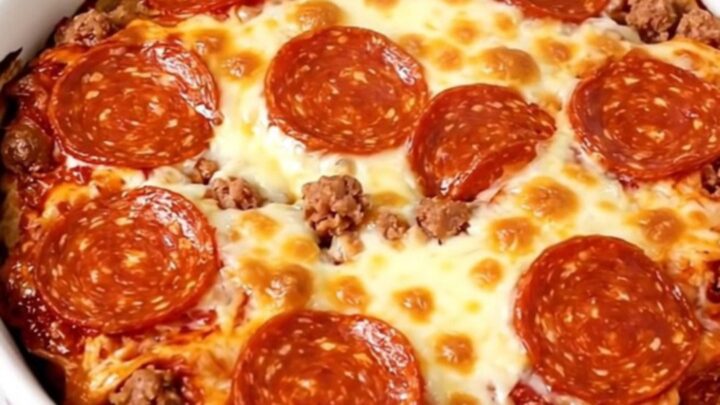 A top-down view of a black slow cooker filled with layers of cream cheese, sausage, mozzarella, and pepperoni before cooking.