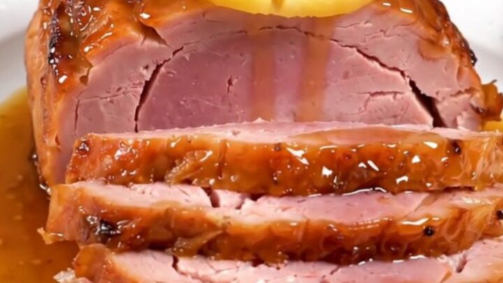 A glistening spiral-cut ham topped with pineapple slices and a rich brown sugar glaze in a slow cooker.