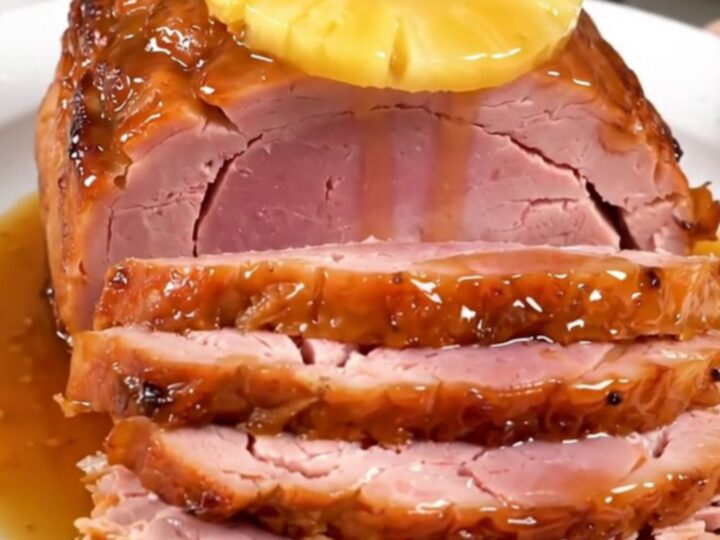A glistening spiral-cut ham topped with pineapple slices and a rich brown sugar glaze in a slow cooker.