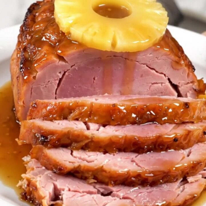 A glistening spiral-cut ham topped with pineapple slices and a rich brown sugar glaze in a slow cooker.
