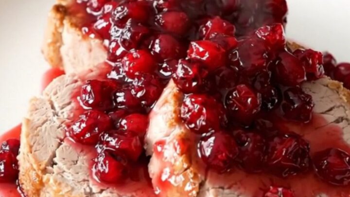 A slow cooker filled with a pork roast, sliced apples, brown sugar, and cranberry sauce.