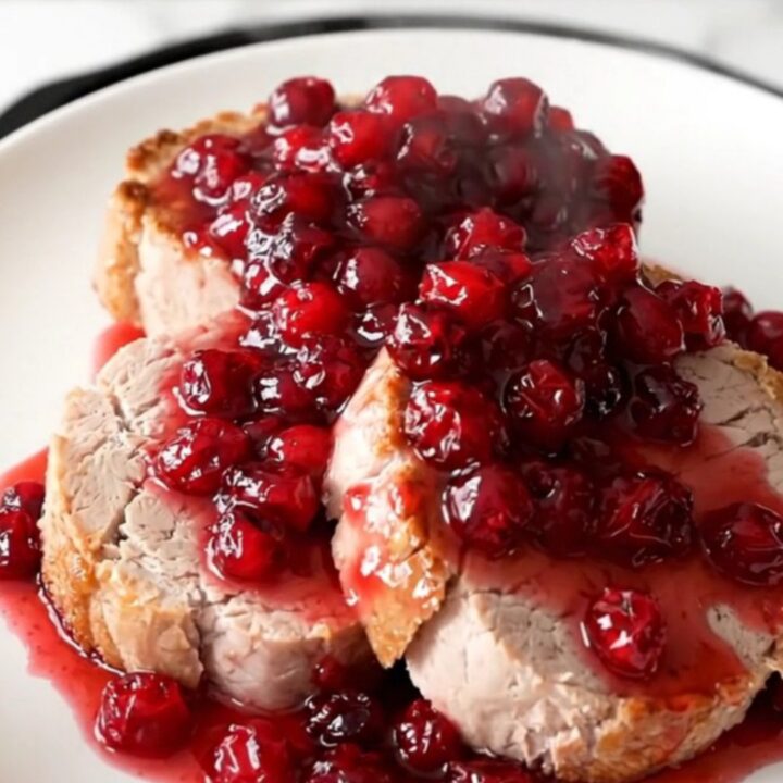 A slow cooker filled with a pork roast, sliced apples, brown sugar, and cranberry sauce.