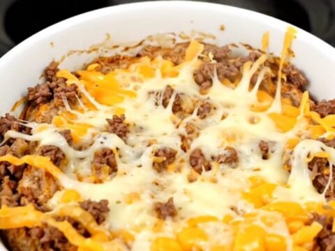 A warm, bubbling bowl of beef enchilada dip in a slow cooker.