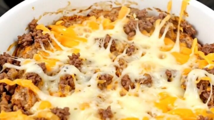 A warm, bubbling bowl of beef enchilada dip in a slow cooker.