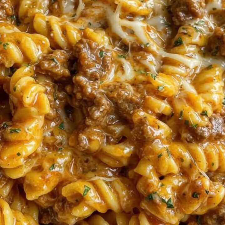 A white bowl filled with glossy rotini pasta, savory ground beef crumbles, and a thick, stretchy melted four-cheese sauce.