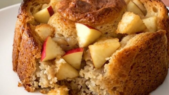 A warm, golden serving of apple cinnamon bread pudding on a white plate.