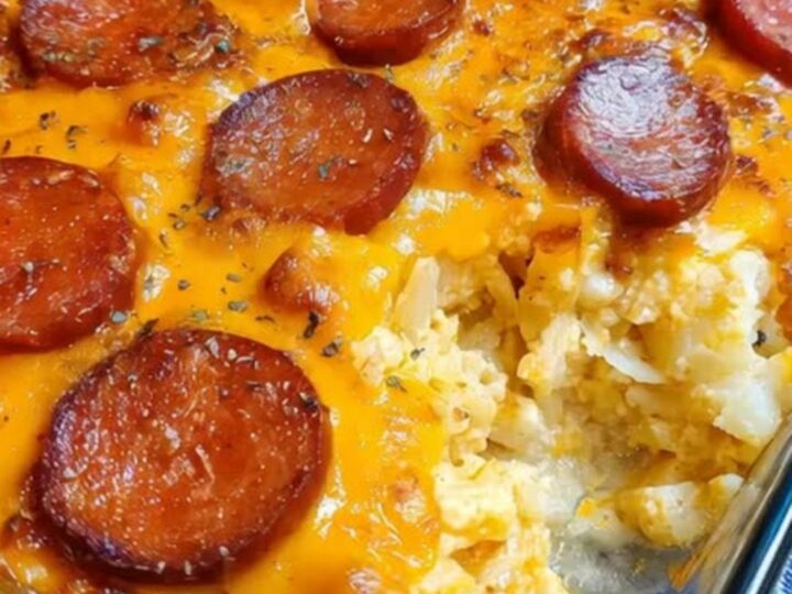 A glass casserole dish filled with bubbling cheesy potatoes and browned smoked sausage rounds fresh from the oven