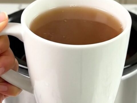 A steaming mug of spiced wassail with cinnamon sticks and cloves on a bright kitchen counter.