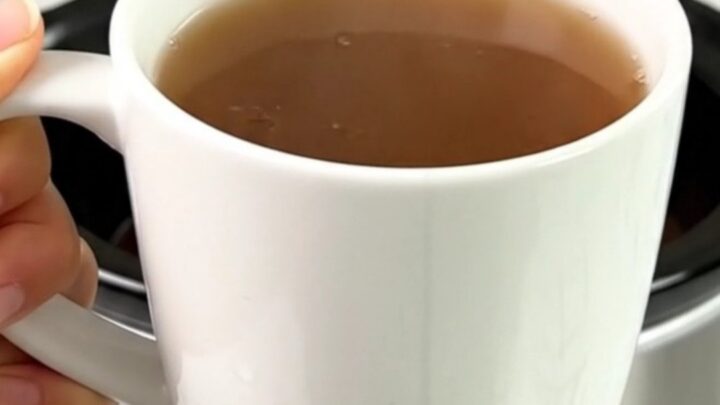 A steaming mug of spiced wassail with cinnamon sticks and cloves on a bright kitchen counter.