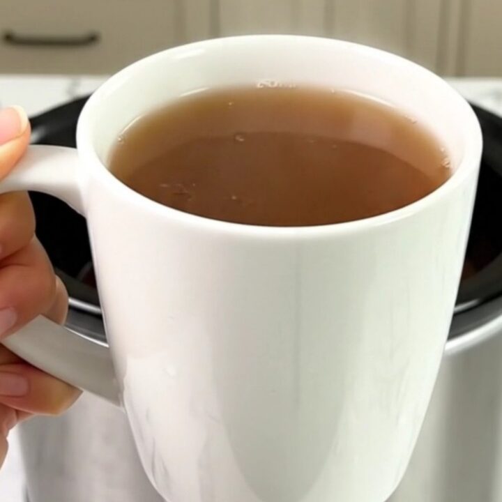 A steaming mug of spiced wassail with cinnamon sticks and cloves on a bright kitchen counter.