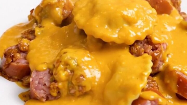 A top-down view of a black slow cooker filled with a creamy pierogi and smoked sausage bake.