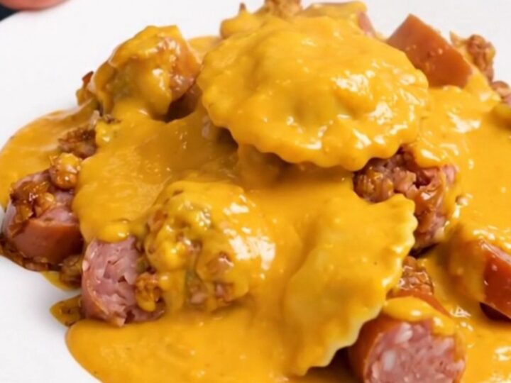 A top-down view of a black slow cooker filled with a creamy pierogi and smoked sausage bake.