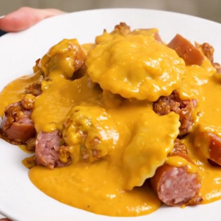 A top-down view of a black slow cooker filled with a creamy pierogi and smoked sausage bake.