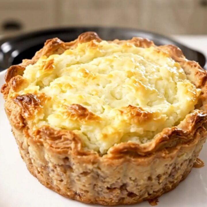 A steaming, hearty portion of slow cooker beef shepherd's pie served on a clean white round plate.