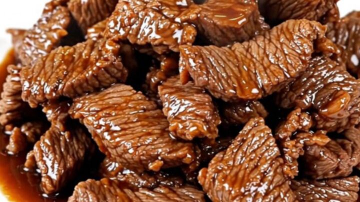 A close-up of tender, glossy Mongolian beef strips served on a white plate.